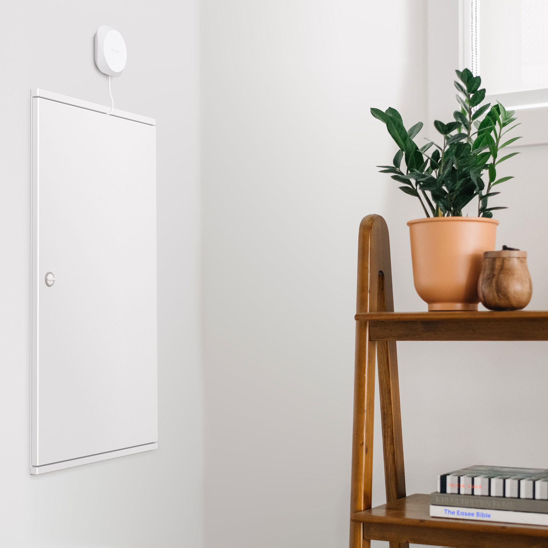 A similar photo of the fuse cabinet. The door is closed, but a wire stretches up from the cabinet to an Easee Equalizer mounted on the wall a few centimeters above the cabinet.